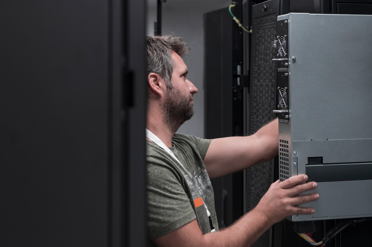 An engineer walks a data-centre aisle between server racks