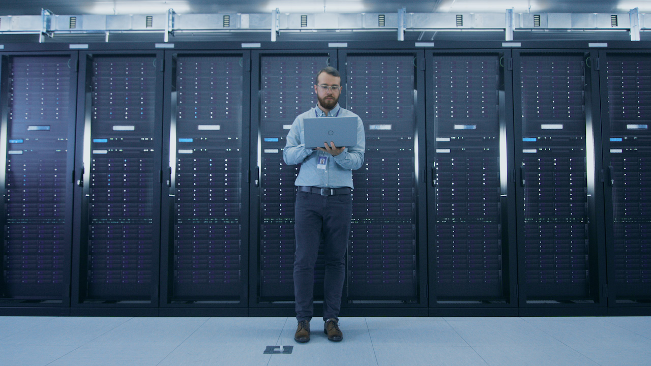 An engineer walks a data-centre aisle between server racks